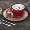 A bowl of yogurt with blueberries and sunflower seeds on a red plate, set on a wooden table. Produktbild-Vorschau
