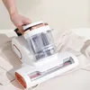 A hand is holding a white and copper handheld vacuum cleaner over a light-colored garment. Produktbild-Vorschau