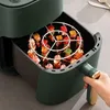 A hand is holding the handle of a green air fryer with a rack of skewers inside. Náhľad obrázku produktu
