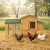 A wooden chicken coop with three chickens in a grassy, straw-covered outdoor setting. Podgląd zdjęcia produktu