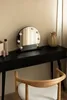A vanity table with a lighted mirror, a vase, and cosmetic products. Náhled obrázku produktu
