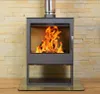 A modern wood-burning stove with a fire burning inside, set against a stone tile wall and wooden floor. Produktbild-Vorschau