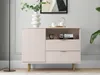 A light pink sideboard with fluted doors and drawers, set against a light gray wall with decorative molding. A white vase with greenery sits on top, along with a teapot and cups on a tray. A floor lamp is visible to the left. Produktbild-Vorschau