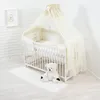 A baby crib with bedding and a teddy bear. Voir les images du produit