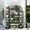 A multi-tiered plant stand filled with various potted plants, displayed outdoors on a patio with sunlight casting shadows. Podgląd zdjęcia produktu