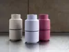 Three spice grinders in different pastel colors are arranged in a row on a metallic surface, with a textured wall in the background. Produktbild-Vorschau