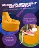 A young boy is playing a video game while sitting on an orange beanbag chair outdoors. Produktbild-Vorschau