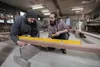 Two men working in a workshop, using a level tool on a wooden beam. Náhľad obrázku produktu