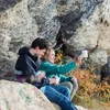 Zwei junge Menschen sitzen auf einem Felsen und genießen Getränke aus dem "Climbing Mug" von YY Vertical; umgeben von herbstlicher Natur. Podgląd zdjęcia produktu