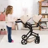 A young girl is playing with a twin doll stroller in a room. Produktbild-Vorschau