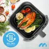 A close-up overhead view of a black air fryer basket containing a cooked salmon fillet, asparagus, grilled garlic, cherry tomatoes, and lemon slices. A blue circular graphic with arrows and text is in the lower left corner, and a blue logo is in the lower  Produktbild-Vorschau