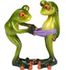 Two green frogs figurines interacting with a purple object. Produktbild-Vorschau