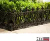 A decorative metal fence in front of green bushes. Produktbild-Vorschau