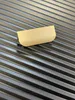 A close-up shot of a gold-colored handle on a black ribbed surface. Náhled obrázku produktu