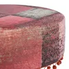 A close-up view of a round ottoman with a patchwork fabric cover in shades of red, pink, and gray. Small orange pom-poms are visible along the bottom edge. Produktbild-Vorschau