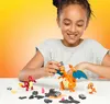 A young girl is building a Mega Pokémon Charmander Evolution Set on a white table. The set includes Charmander, Charmeleon, and Charizard figures, along with building bricks. Náhled obrázku produktu