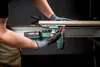 A person is using a cordless jigsaw to cut a piece of wood, with sawdust flying. Voir les images du produit