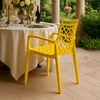A yellow chair is placed on a patio next to a table set for a meal. Produktbild-Vorschau