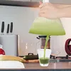 A person is squeezing green juice from a bag into a glass. Produktbild-Vorschau