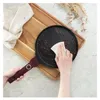 A hand is cleaning a pan with a cloth on a wooden board. Náhľad obrázku produktu