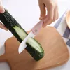 A person is slicing a cucumber on a wooden cutting board with a ceramic knife. Voir les images du produit