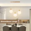 A dining room with a table and chairs, featuring a pendant light fixture above the table. Voir les images du produit