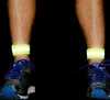 Close-up of a person's legs wearing running shoes and reflective ankle bands. Náhled obrázku produktu