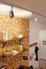 A room with brick walls, shelves, and track lighting. Anteprima dell’immagine prodotto