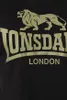 A close-up of a black t-shirt with a gold Lonsdale logo and the word LONDON printed on it. Produktbild-Vorschau