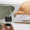 A hand is using a wrench to tighten a fitting on a sink. Produktbild-Vorschau