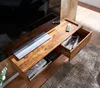 A wooden TV stand with a drawer open, showing some items inside, and a remote control on top. Produktbild-Vorschau