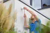 A man is installing a motion detector on the exterior wall of a building. Produktbild-Vorschau