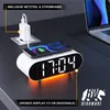 A digital alarm clock with a phone charging on top, placed on a desk next to a laptop. Anteprima dell’immagine prodotto