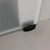Close-up of the bottom corner of a frosted glass sliding door with a black door stop on a concrete floor. Anteprima dell’immagine prodotto