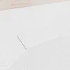 A close-up, angled view of a white shower tray with a textured surface and a rectangular recessed area for a drain. Produktbild-Vorschau