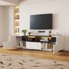 A modern living room with a TV mounted on the wall above a sleek, white and black TV stand. The stand has open shelves and closed cabinets, some with LED lighting. Produktbild-Vorschau