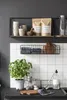 A kitchen counter with various items including a plant, jars, cutting boards, and shelves with kitchenware. Produktbild-Vorschau