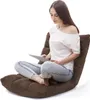 A woman is sitting on a brown floor chair and using a tablet. Produktbild-Vorschau