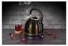A black electric kettle is shown steaming next to a glass of red tea, with dried petals scattered around. Náhled obrázku produktu