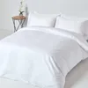 A neatly made bed with white bedding and pillows, next to a small side table with a plant. Produktbild-Vorschau