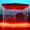 Red net lights are draped over an outdoor umbrella and illuminate a wooden deck at dusk. Produktbild-Vorschau