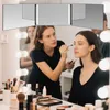 A makeup artist applies makeup to a model in front of a lighted vanity mirror. Produktbild-Vorschau