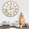 A vintage-style wall clock is displayed on a white wall above a wooden countertop with various kitchen items. Produktbild-Vorschau