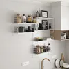 A modern kitchen with white tiled walls, featuring modular white wire shelving units mounted on the wall, displaying various kitchen items like jars, bottles, dishes, and decorative items. Voir les images du produit