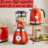 A collection of retro-style kitchen appliances, including a toaster, blender, and kettle, are displayed on a countertop and a wooden shelf. A smoothie and some fruit are also visible. Anteprima dell’immagine prodotto