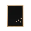 A black chalkboard with a wooden frame and four small wooden magnets attached to the bottom right corner, presented on a white background. Produktbild-Vorschau
