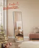 A bedroom decorated for Christmas with a full-length mirror, a Christmas tree, and gifts. Produktbild-Vorschau