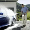 A man is washing a car with a pressure washer. Produktbild-Vorschau