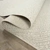 A close-up view of a rolled-up rug with a textured pattern, placed on a wooden floor. Náhled obrázku produktu