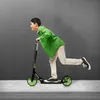 A boy is riding a scooter on a sidewalk in front of a gray wall. Náhľad obrázku produktu